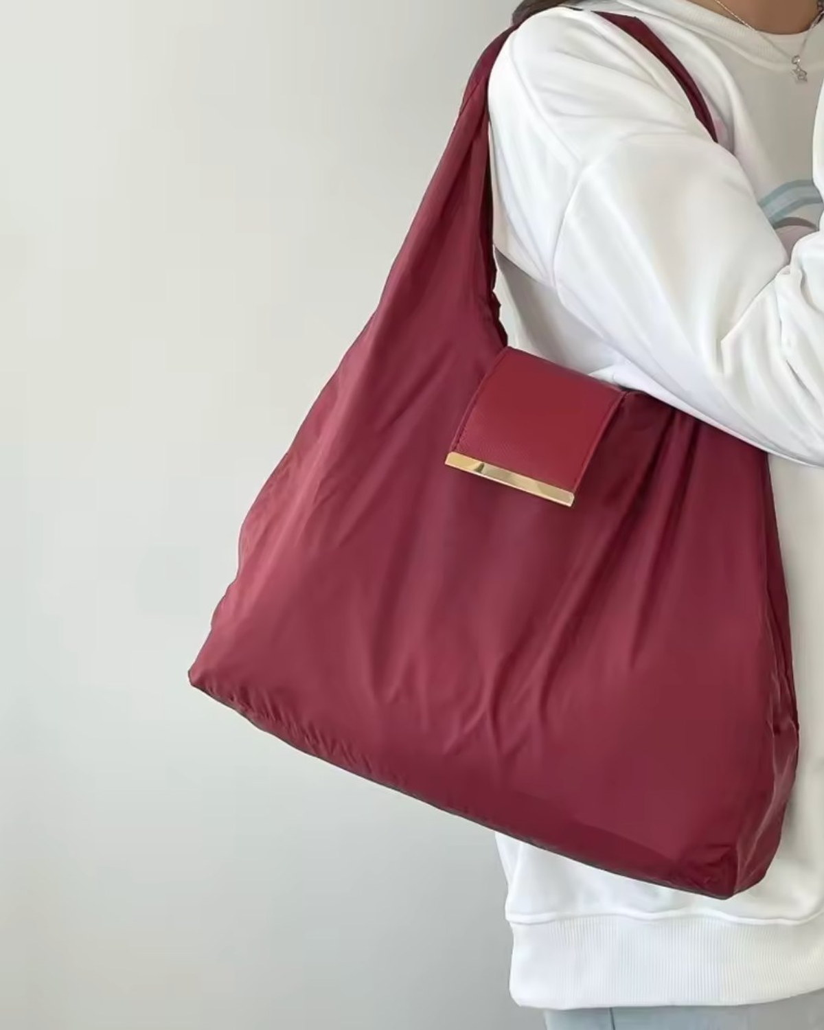 TOTEGO Rouge déplié, porté à l'épaule, barre dorée visible
